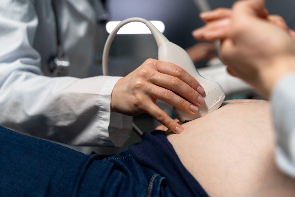 healthcare professional performing an ultrasound on a patient abdomen